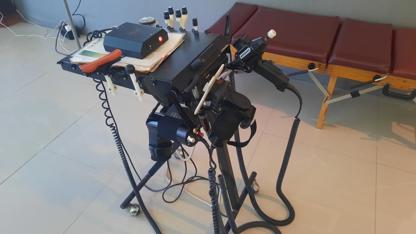 The ArthroStim and percussor instruments on their cart beside an adjusting table
