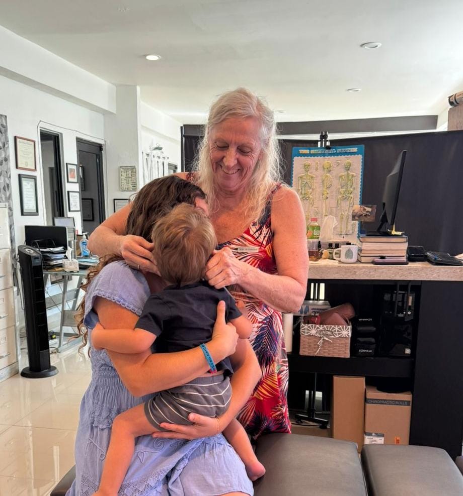 Dr. Susan Colby adjusting a young child held by their mother