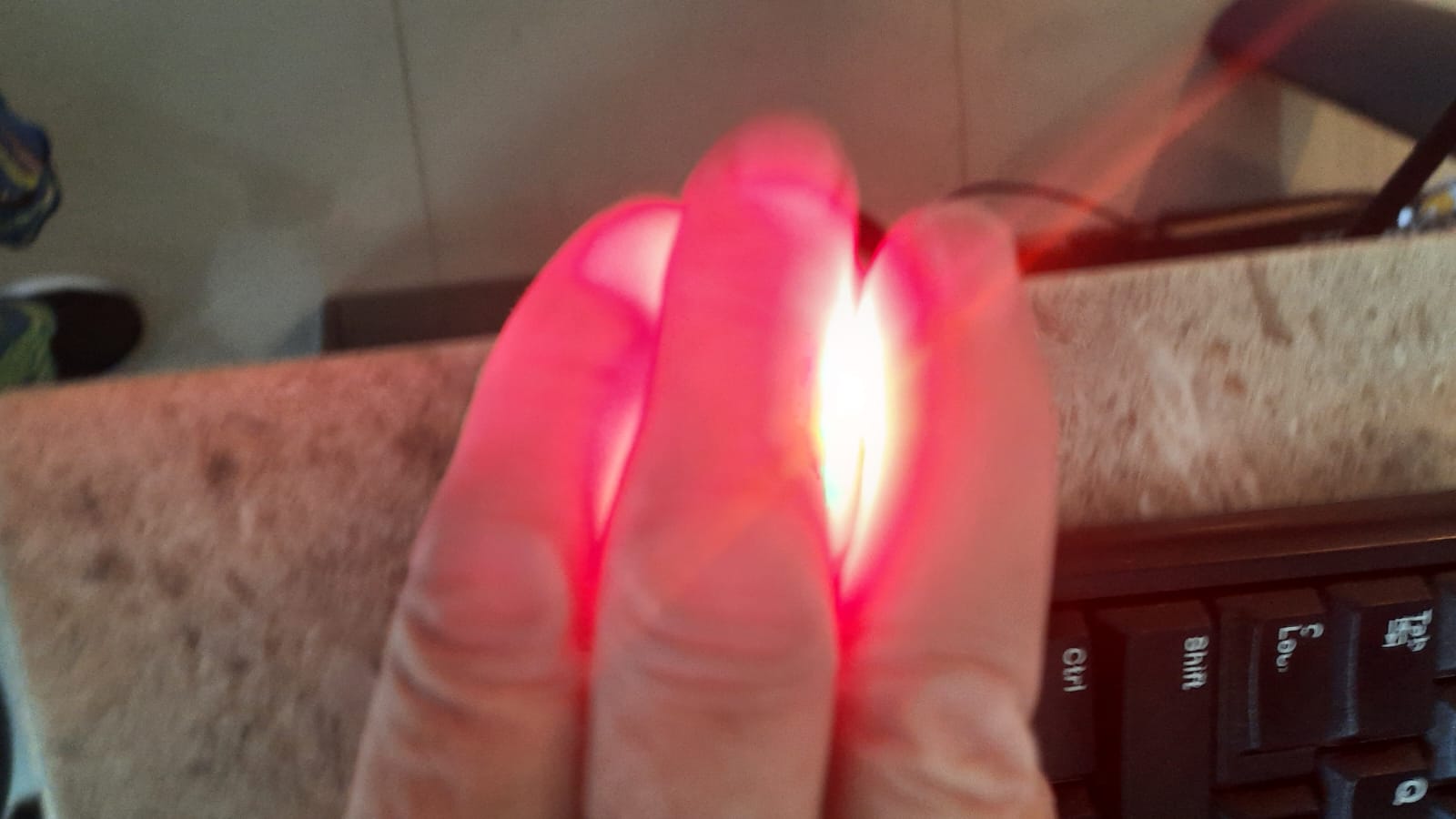 Red therapy light shining through fingers, showing how deeply the light penetrates tissue
